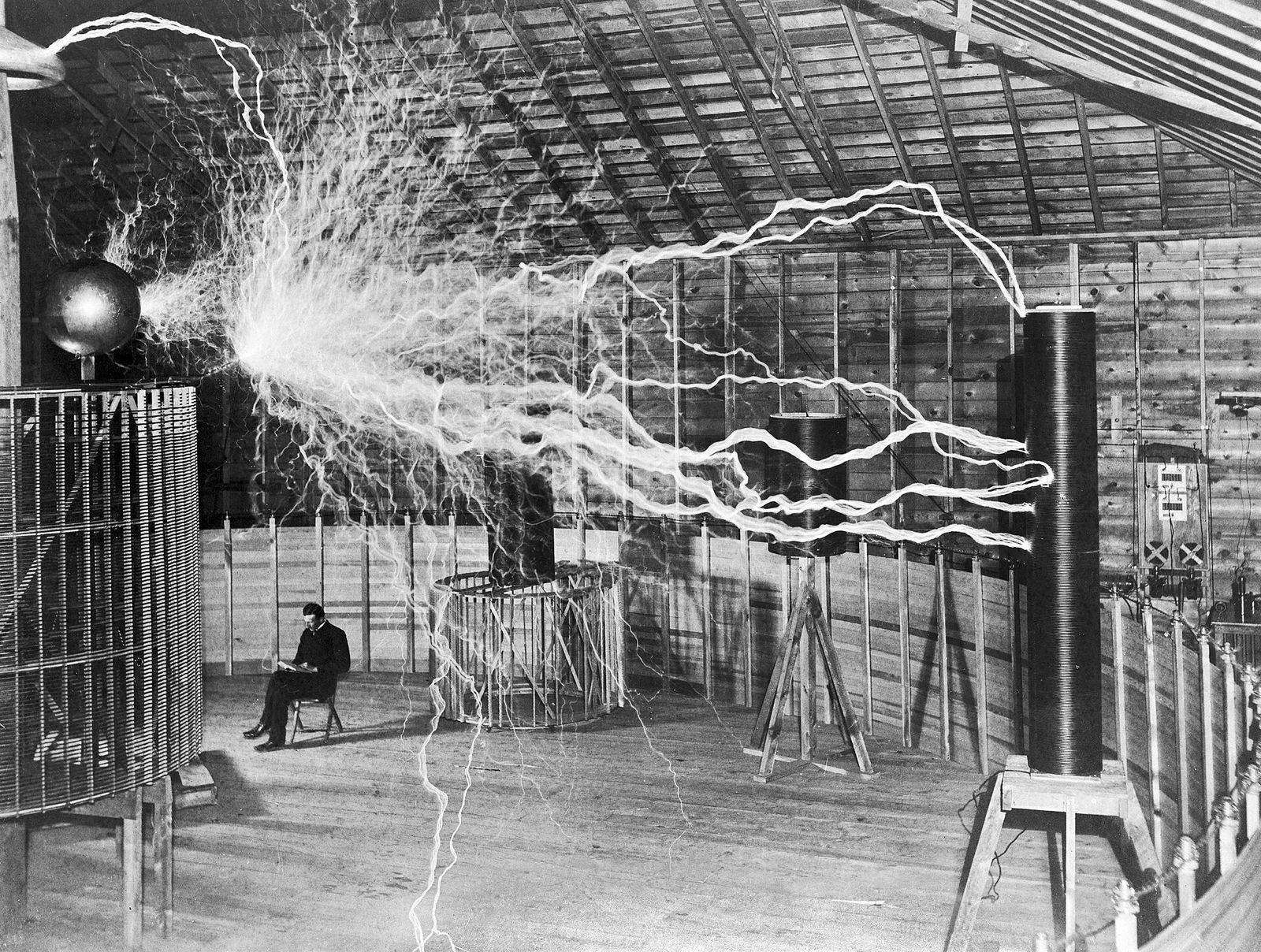 Nikola Tesla in his Colorado Springs laboratory in 1899, seated amid electrical discharges