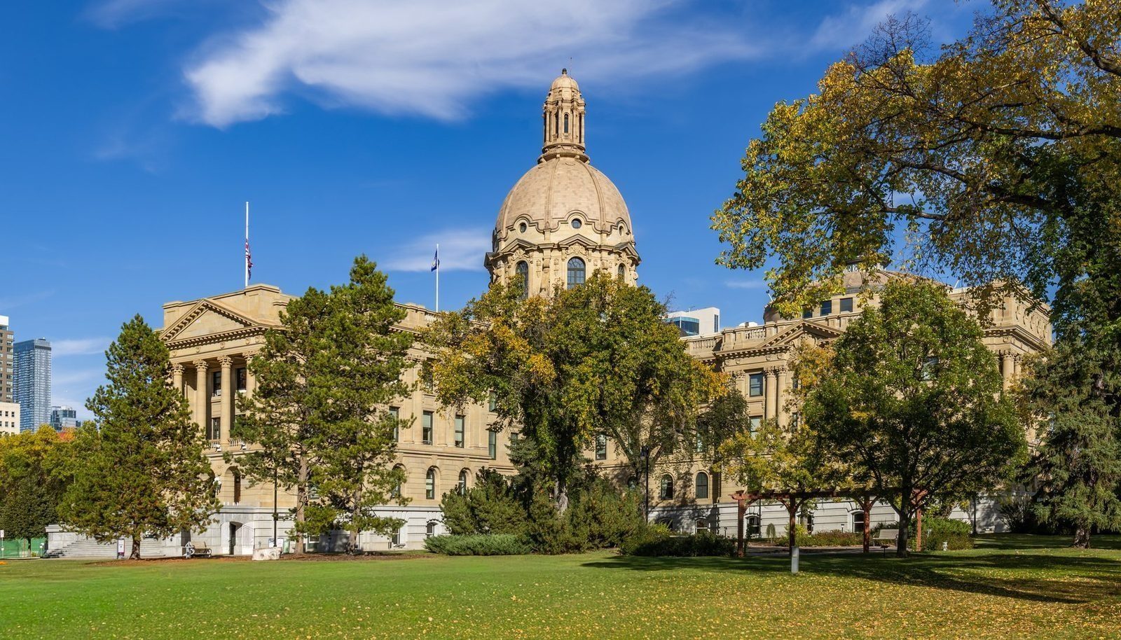 The Alberta Legislature Building in Edmonton, its dome flying the Canadian flag, photographed in autumn.