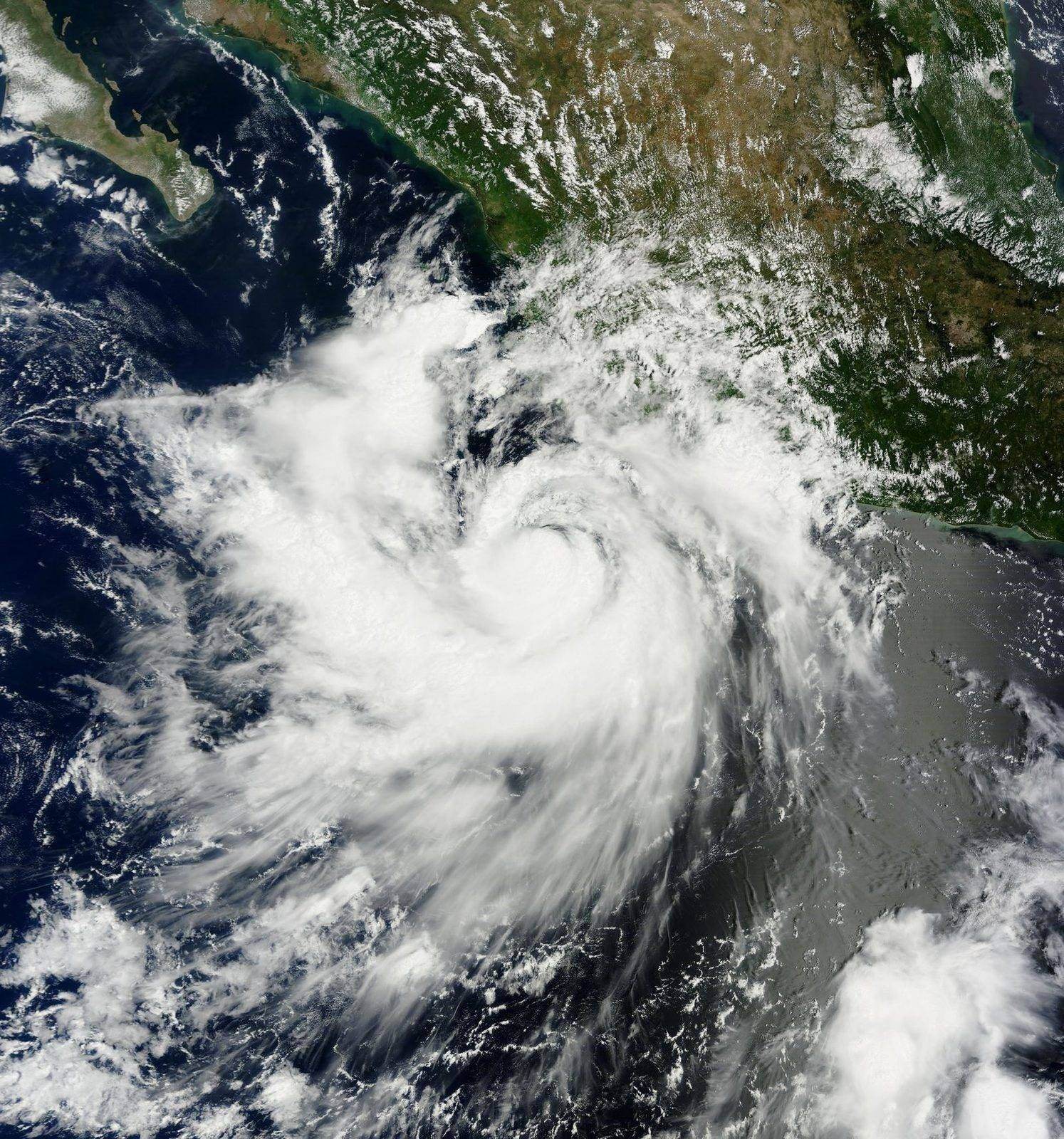 Satellite view of a hurricane swirling over warm ocean waters, showing spiral cloud bands around a defined central eye